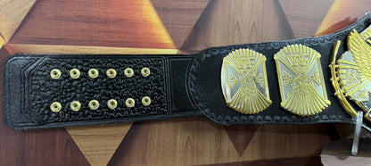Black championship belt with gold medallions on a wooden surface