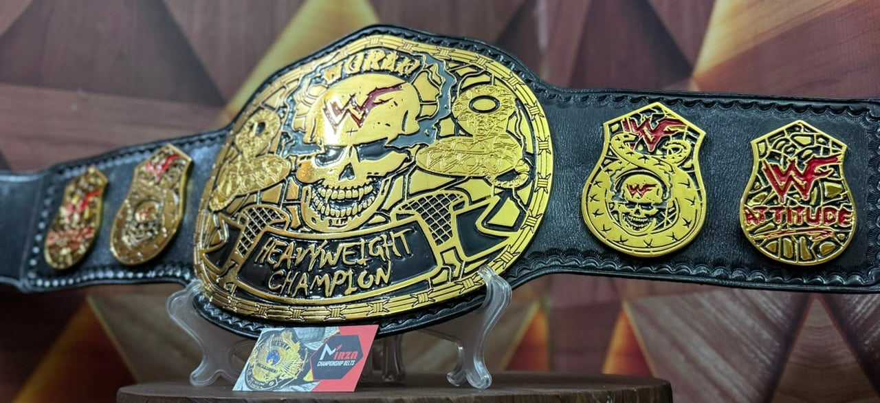 A WWE Hardcore Championship belt displayed on a small stand, featuring a large gold central plate with a skull and lion design, black leather strap, and multiple gold and red championship emblems.